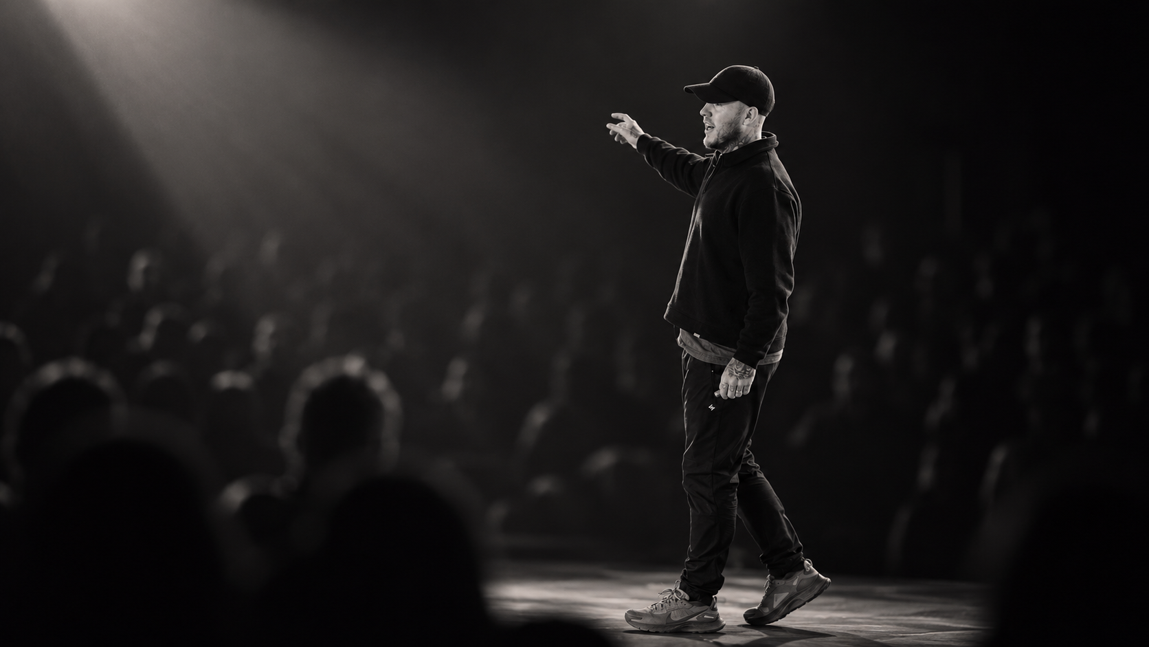 Oly Newton speaking on stage under a spotlight, seen from the side